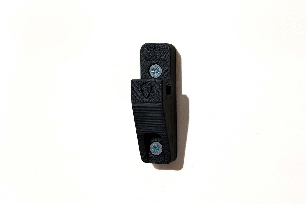 Black wall mount bracket for LEGO Technic Koenigsegg Sadair's Spear 42232 fixed to a wall with two screws.